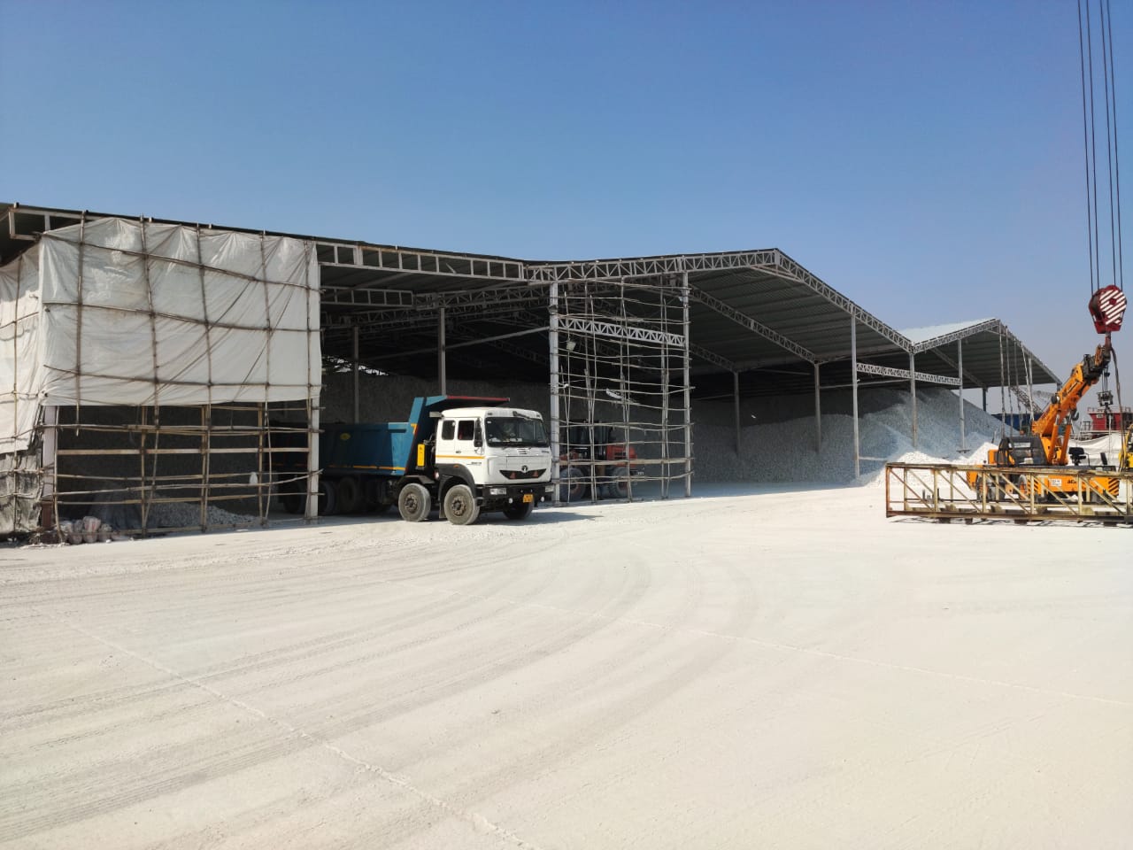 Steel warehouse sheds with bulk material, a truck and a crane
