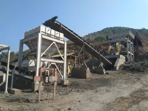 A conveyor and screening plant beside a rocky hillside