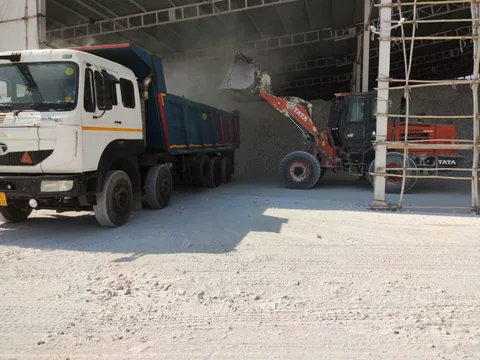 A wheel loader filling a tipper truck inside a bulk-material warehouse